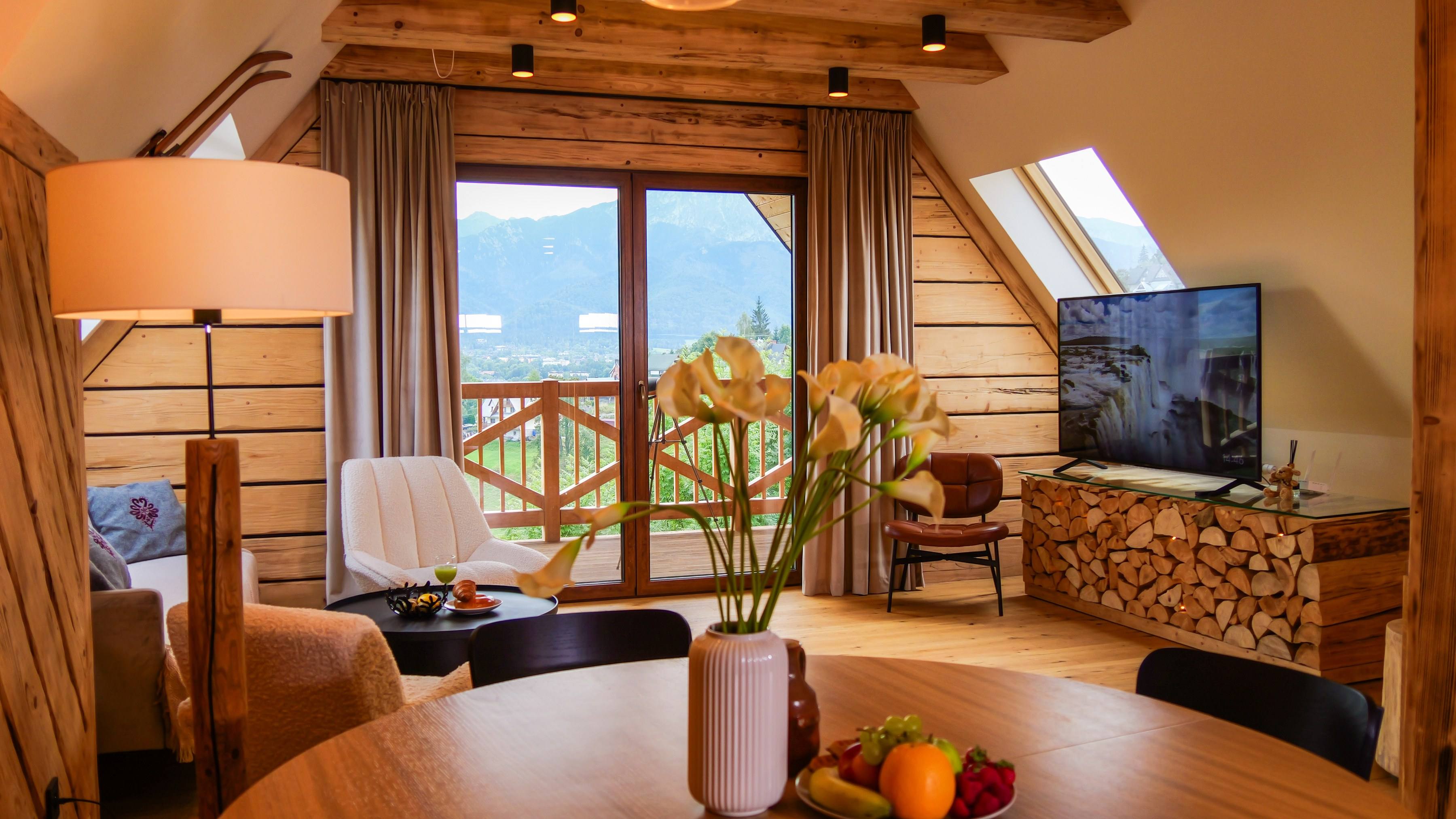Salon apartamentu w Apart H900: drewniane ściany, balkon w krzyżulce i Tatry za oknem